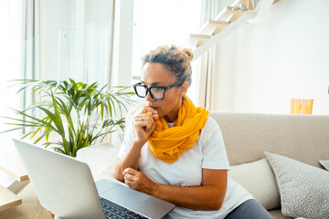 Wall Mural - One woman using laptop sitting on sofa in cozy apartment. Window lights in background. Female people enjoying technology in indoor leisure activity reql life. Surfing the net alone browsing web pages