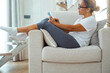 © simona - One woman sitting on chair and using mobile phone scrolling social media content or browsing the web searching news chilling and relaxing in indoor leisure activity with technology and wifi connection