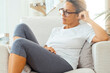 © simona - Calm peaceful lazy adult homeowner woman resting in armchair looking and thinking alone relaxing and chilling, sporty wear clothes, enjoying peace, leisure, comfort, meditating at home. Indoor room