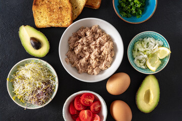 Poster - Set ingredients for cooking healthy sandwich with avocado, tuna, eggs, cherry tomatoes and fresh microgreens on a dark background top view