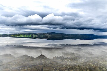 Wall Mural - a reflection of clouds in water near mountains and hills at low tide