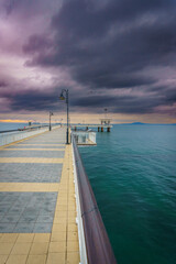 Wall Mural - Pier extending into the water at sunset.