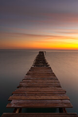 Sticker - sunrise seascape with an old wooden dock leading out into the calm ocean waters