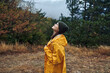 © SHOTPRIME STUDIO - A woman wearing a yellow raincoat standing in the middle of a lush field surrounded by trees and nature