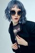 © Lina Solntseva  - a beautiful woman with purple hair wearing round sunglasses on a blue background
