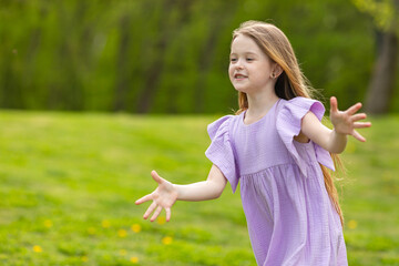 Wall Mural - Cute happy laughing little girl having fun on the grass in the meadow in the park, playing on a warm sunny weekend. lifestyle. space for text. High quality photo