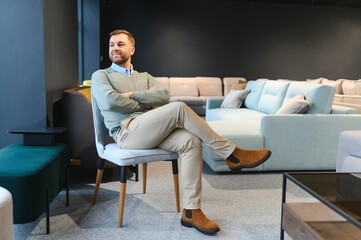 Canvas Print - A handsome young man chooses furniture in a store