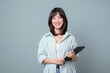 © Jirawatfoto - young enterpriser manager, asian working woman holding tablet and smiling, standing over green background