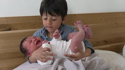 young boy holding crying newborn baby in his arms, sibling care and bonding, tender family moment, b