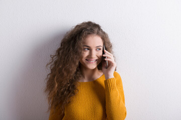 Canvas Print - Portrait of a gorgeous teenage girl with curly hair, making phone call. Studio shot, white background with copy space