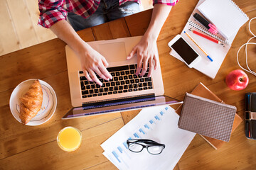 Wall Mural - Top view on desk of university student is writing her thesis on a laptop, sitting at home on the couch.