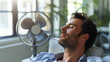 © Anastasiia - Man relaxing in front of a fan, cooling off indoors on a hot day