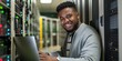© gunzexx png and bg - A cheerful tech professional is working on a laptop in a modern server room, surrounded by server racks, indicating IT expertise