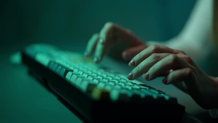 Closeup hands of unrecognizable female programmer using typing on backlit desktop keyboard computer working late evening. Woman fingers typing colorful keyboard at night, sitting at home office.