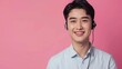 © VISUAL BACKGROUND - Young man smiling while wearing headphones against pink background.