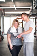 © Halfpoint - Overweight woman consulting with trainer, discussing daily workout plan. Personal trainer talking with client, discussing exercise program in gym.