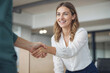 © polack - A woman shakes hands with a man in a business setting. The woman is smiling and she is happy. Contract signing concept