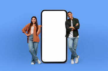 Wall Mural - A man and a woman are standing next to a large screen phone, examining the display, woman is pointing at the phone screen, seemingly engaged in the content.