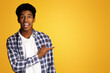 © Prostock-studio - Excited Afro Guy Pointing Aside and Looking at Camera, Yellow Studio Background