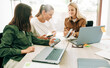 © Ilona - Female colleagues analyze social media marketing at a business meeting using mobile phone and laptops.
