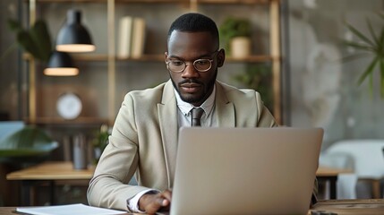 Canvas Print - businessman, in a beige suit, analyzing financial data on his laptop