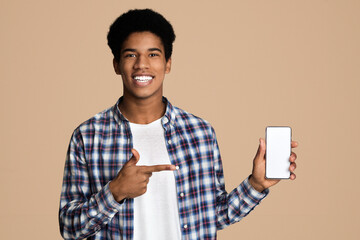 Poster - Smiling african-american guy holding smartphone with blank screen and point at it, copy space