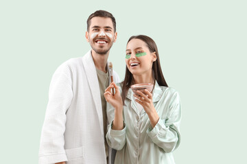 Poster - Young loving couple with facial mask on green background