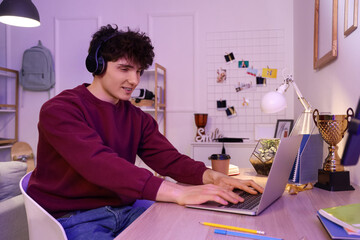 Wall Mural - Male student studying while streaming at home in evening