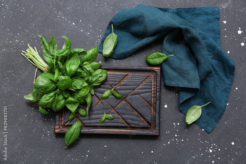 Board with fresh green basil leaves on black background