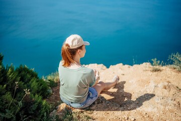 Wall Mural - A woman is sitting on a rock overlooking the ocean