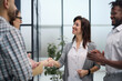 © Katsiaryna - Business people standing and shaking hands in an office building