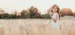 © Satori Studio - A woman is standing in a field of tall grass, wearing a straw hat and a white dress. She is smiling and she is enjoying the outdoors