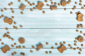 Dry dog food treats and kibble on blue and white background.  Round and bone shaped.  Border.