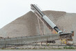 © Dolores  Harvey - A stockpile of bulk limestone mined in an above ground quarry. The beige pelleted crushed sedimentary rock of magnesium carbonate and calcium in raw form is piled in a mound. The background is white.
