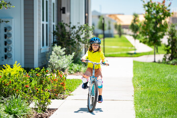 Wall Mural - Child riding bicycle. Little kid boy in helmet on bicycle along bikeway. Happy cute little boy riding bicycle in summer park. Child in protective helmet for bike cycling on bicycle. Kid riding bike.