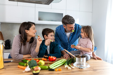 Wall Mural - Overjoyed young family with son and daughter have fun cooking diner or lunch at home together, happy smiling parents enjoy weekend play with small children doing cooking in kitchen