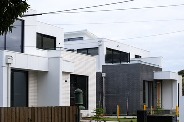 A newly built modern suburban home with a contemporary exterior design. The construction site of two story homes is nearly finished. Concept of real estate, home ownership and housing