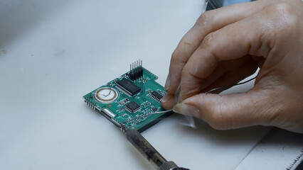 Poster - Close up of engineer does computer motherboard soldering. Creative. Painstaking work of soldering a chip.