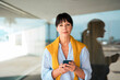 © Westend61 - Confident businesswoman holding mobile phone in front of glass wall