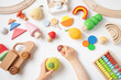 © juliasudnitskaya - Toddler children activity for motor and sensory development. Baby hands with colorful wooden toys on table from above.