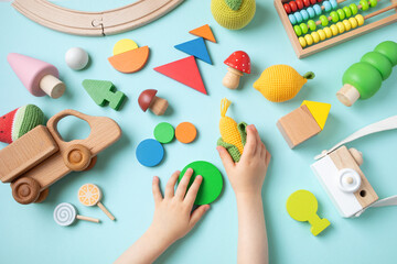 Toddler children activity for motor and sensory development. Baby hands with colorful wooden toys on table from above.