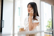 © bongkarn - A confident Asian businesswoman is having a serious phone conversation in the company's corridor.