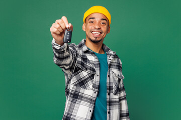 Poster - Young smiling happy man of African American ethnicity he wear shirt blue t-shirt yellow hat hold give car key fob keyless system isolated on plain green background studio portrait. Lifestyle concept.