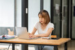 © Thitisak - Asian business woman working on computer looking at documents at office
