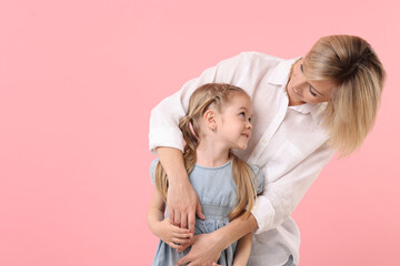 Poster - Family portrait of happy mother and daughter on pink background. Space for text