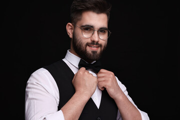 Wall Mural - Portrait of smiling man in shirt and bow tie on black background