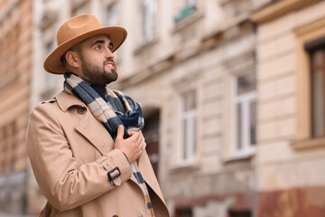 Wall Mural - Handsome man in warm scarf on city street. Space for text