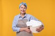 © New Africa - Happy housewife with basket full of laundry on orange background