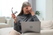 © New Africa - Overwhelmed woman with laptop sitting on sofa at home