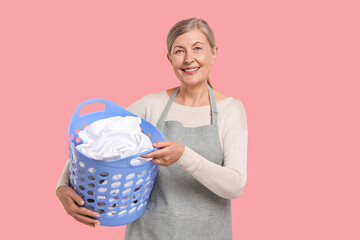 Canvas Print - Happy housewife with basket full of laundry on pink background